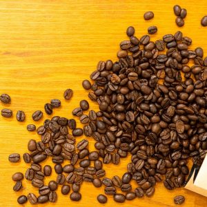 Granos de café tostado saliendo de una bolsa kraft